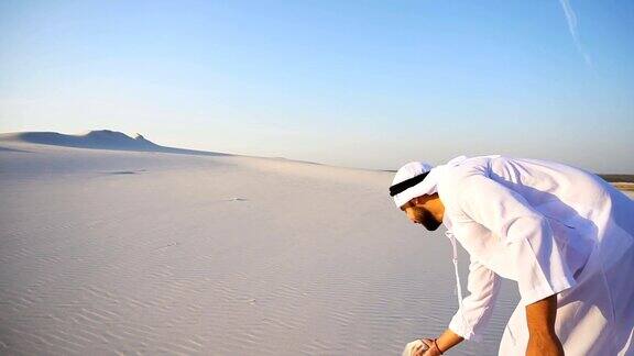在晴朗的夏日快乐的阿拉伯酋长走在沙漠的顶端脸上带着微笑