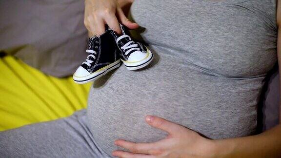 肚子上放着婴儿鞋的孕妇