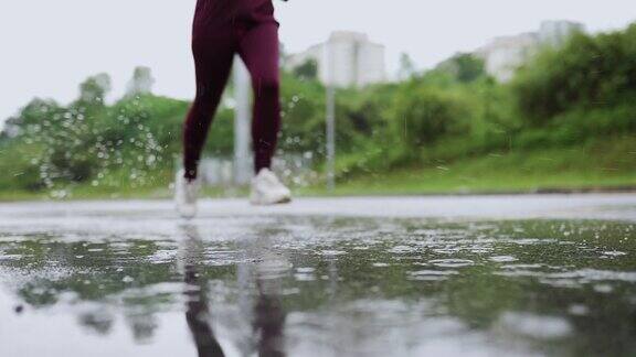 亚洲华人运动员女性在运动服装是慢跑在街道上的雨