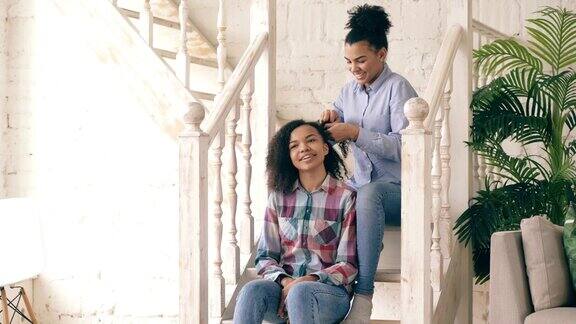 两个非洲裔美国卷发女孩姐妹互相取笑卷曲的发型并在家里有乐趣
