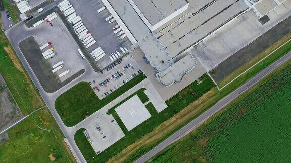 绿色田野上的工厂从上面俯瞰工业区域和附近的许多汽车白色卡车停在停车场鸟瞰图
