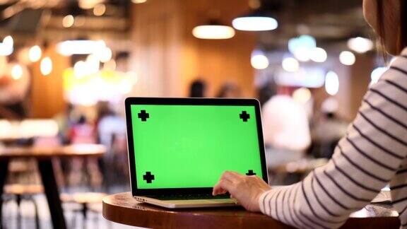 在咖啡馆和餐厅使用笔记本电脑绿屏的女人