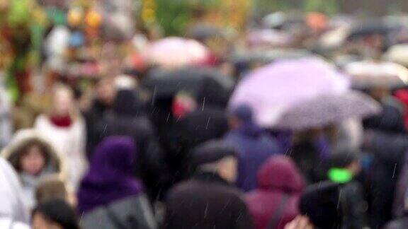 人们在繁忙的商业街撑着雨伞挡雨真正的时间人们在雨中带着雨伞上下班模糊的散景雨天的城市街道的自然背景