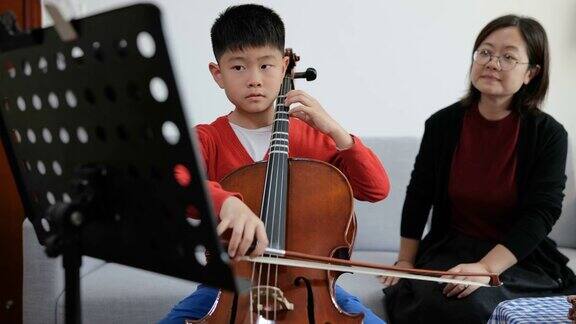 小男孩在家与老师练习大提琴