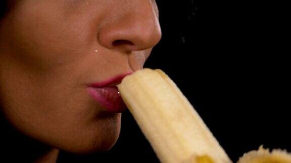 慢动作的性感年轻女子诱人地吃一个新鲜的香蕉