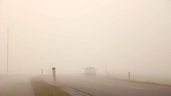 汽车行驶在空旷的雾蒙蒙的道路上