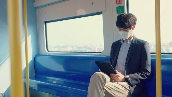 商人戴着医用口罩在公共交通工具上玩平板电脑