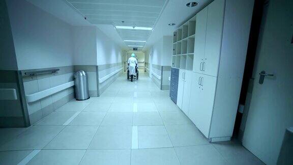 护士正用轮椅载着一个病人沿着走廊走