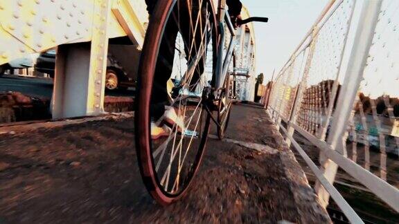 在阳光明媚的日子里骑自行车的人用固定齿轮运动自行车在桥上行走