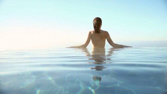 在俯瞰大海的无边泳池里一个女人正在湿头发