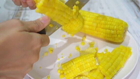 把煮熟的玉米粒从玉米芯上切下来放在盘子里