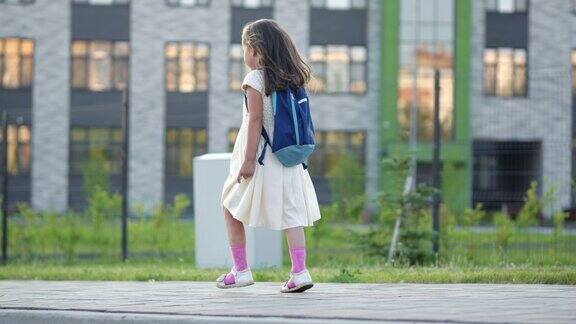 一个背着书包的学龄前女孩走过教学楼