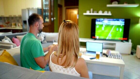 在家里一对年轻夫妇在电视上看足球比赛