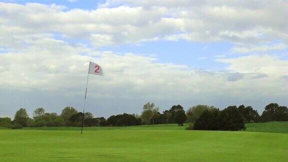 绿色的高尔夫球场洞和旗帜在一个风晴天