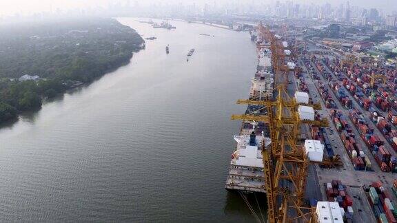 日落时分无人机与起重机在国际港口上空飞行的4k镜头鸟瞰图