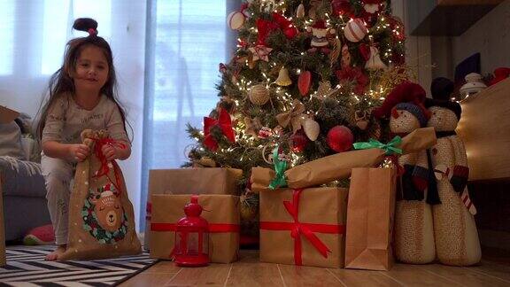 可爱的孩子穿着睡衣在圣诞节早上打开礼物袋