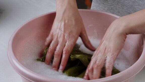 用泡沫和洗衣粉在盆里洗绿色毛巾用洗衣粉洗脏衣服洗衣概念手洗去污剂的广告