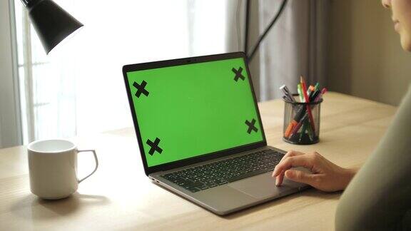 亚洲妇女在家里使用绿色屏幕的笔记本电脑