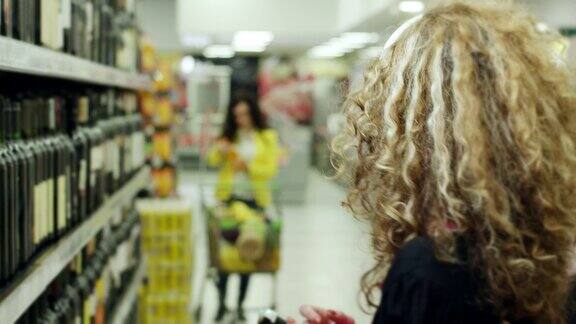 女人在超市挑选葡萄酒和戴着耳机听音乐