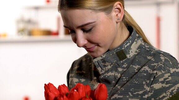 漂亮女人的军装闻着郁金香花束退伍军人节爱国主义