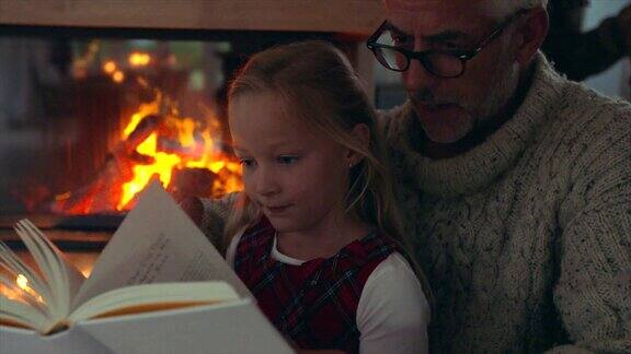 小女孩和爷爷在壁炉旁边看书