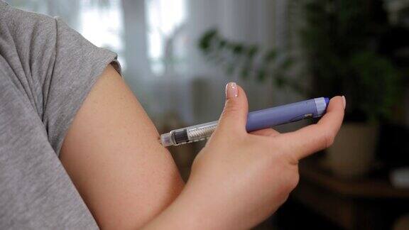 一个年轻女人用胰岛素笔向她的手臂注射胰岛素的特写