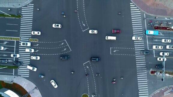 无人机拍摄的城市十字路口汽车和公交车行驶在大道上在日落时分相机移动