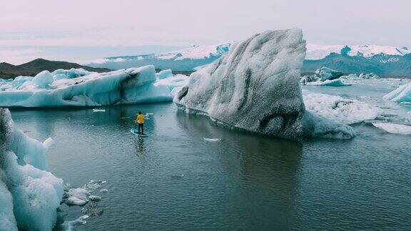 鸟瞰图站立桨板划水冰川泻湖与巨大的冰山