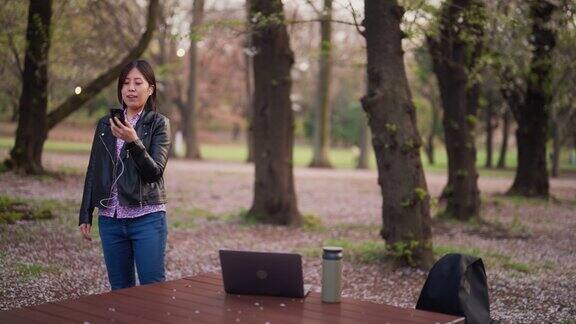 一名年轻女子在公园用笔记本电脑进行视频通话
