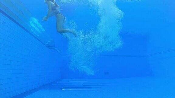 一名女潜水员在一团气泡中降落在游泳池的水下视图