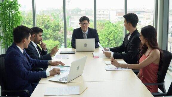 一群亚洲商务人士在高层办公室开会讨论Windows首席执行官经理在会议室与公司业务团队谈话