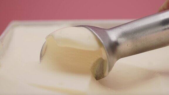 用不锈钢勺从容器中舀出香草冰淇淋