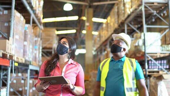 同事们戴着口罩在配送仓库开会
