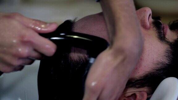 一名理发师在理发店里给一位男顾客洗头