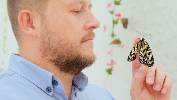 一只雄性的手拿着一只蝴蝶仔细地观察它欣赏着这只昆虫的美丽