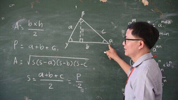 在课堂上男老师用白色粉笔在黑板上写字来教学生
