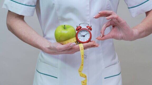 营养学家医生健康生活方式概念-拿青苹果闹钟和卷尺