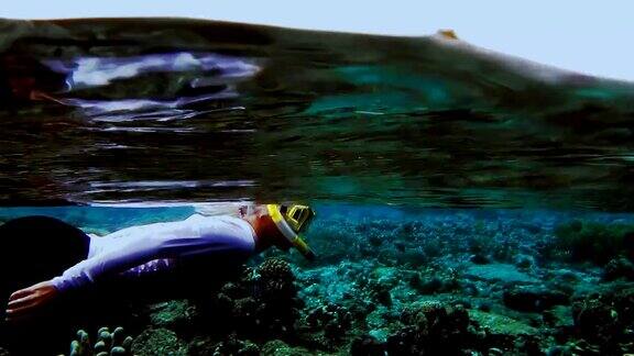 女性浮潜uv泳衣沿着美丽的珊瑚礁Gam岛在海洋表面上的背景拉贾安帕西巴布亚印度尼西亚