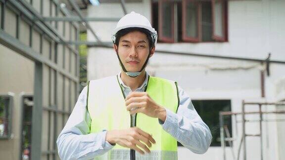 亚洲同事、工人、戴安全帽和眼镜的人的肖像建筑现场男工程师双手交叉站着微笑着看着镜头