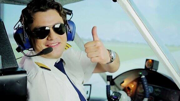 快乐的男飞行员戴着太阳镜对着镜头微笑竖起大拇指做手势