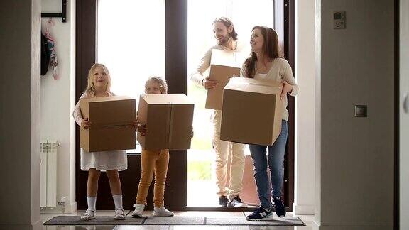 幸福的家庭和孩子们拿着箱子打开门进入房子