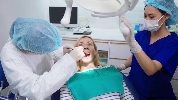 女牙医在牙科诊所为白人女孩检查牙齿美女病人躺在牙科椅上在医院预约手术期间接受医生的牙科治疗