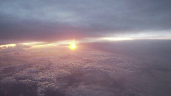 从飞机窗口座位俯瞰日落破碎的云层使地形阴云密布