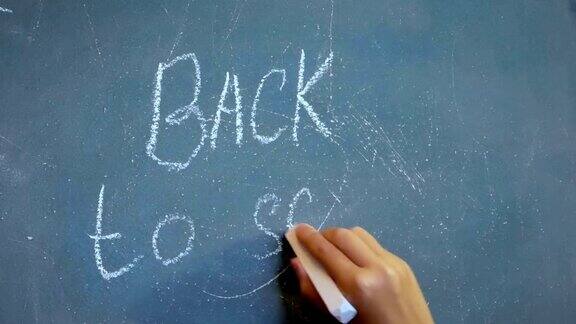 孩子的手在黑板上写着“回到学校!”