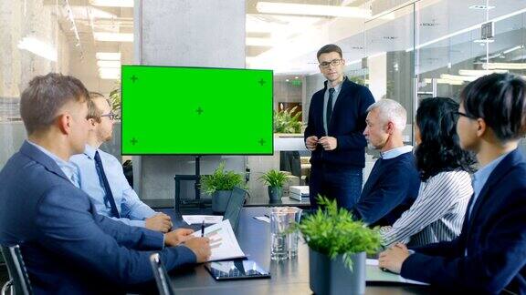 商人指着绿色色度键屏幕墙电视做报告