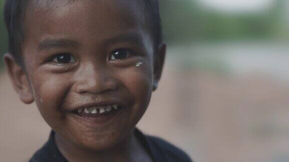 幸福可怜的男孩在房子旁边玩耍时微笑的肖像