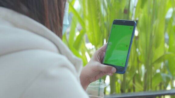 近距离女子拿着智能手机在手里与色度键绿色屏幕在咖啡馆