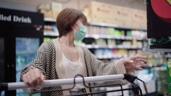亚洲妇女使用污染口罩在超市购物车