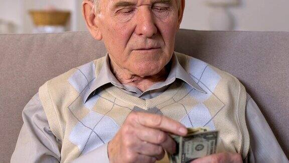 坐在沙发上数钱的老年男性特写生活水平低补贴
