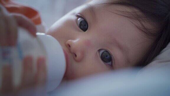 婴儿的特写:喝牛奶的婴儿眨着眼睛